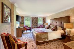 a hotel room with a bed and a desk and chairs at Grosvenor Pulford Hotel & Spa in Pulford