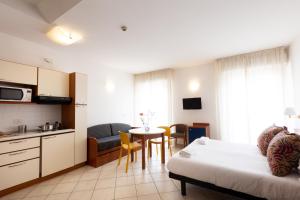 a hotel room with a bed and a kitchen and a table at Residence Mimosa in Rimini