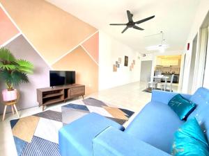 ein Wohnzimmer mit einem blauen Sofa und einem TV in der Unterkunft De'Colour Stay at Country Homes Rawang in Rawang