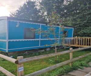 uma pequena casa azul num quintal ao lado de uma cerca em Glamping Hut - Riverview 3 em Welshpool