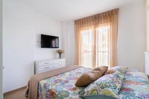 a bedroom with a bed and a tv on a wall at Apartamentos Delamar in Carboneras