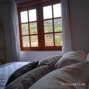 uma cama em frente a uma janela num quarto em A Casa Azul - Igatu em Igatu