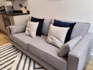 a gray couch with pillows on it in a living room at Stunning mill apartment near to city centre and Etihad stadium! in Manchester