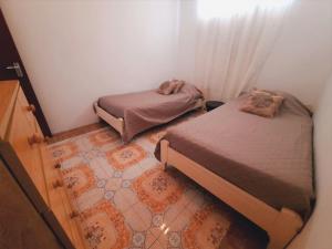 a small room with two beds and a rug at Chaleureuse maison située a 1 minute de la plage in Le Morne