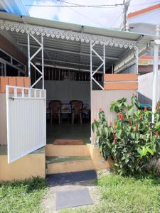 a patio with a white gate and a table and chairs at Chaleureuse maison située a 1 minute de la plage in Le Morne
