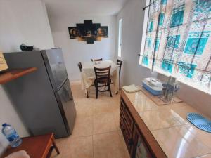 eine Küche mit einem Tisch und einem Kühlschrank in der Unterkunft Chaleureuse maison située a 1 minute de la plage in Le Morne