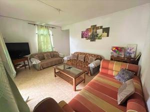 ein Wohnzimmer mit 2 Sofas und einem TV in der Unterkunft Chaleureuse maison située a 1 minute de la plage in Le Morne