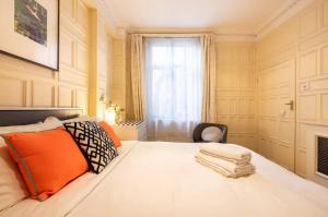 a bedroom with a bed with orange pillows and a window at Pass the Keys Cosy 1 bedroom flat in Knightsbridge in London