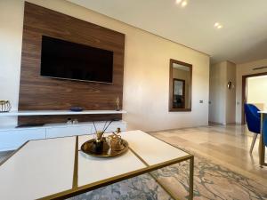 a living room with a tv on a wall at Agate 212 Lovely 2-bedrooms apartment with pool & golf view in Marrakech