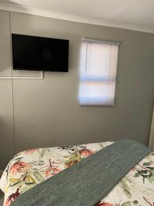 a bedroom with a bed with a flat screen tv on the wall at Gussella Lodge in East London