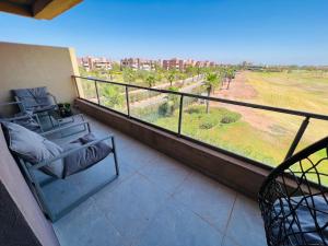 einen Balkon mit einem Stuhl und Blick auf ein Feld in der Unterkunft Agate 212 Lovely 2-bedrooms apartment with pool & golf view in Marrakesch