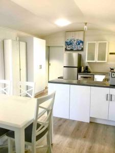a kitchen with white cabinets and a white table and chairs at SALT @ North Beach WALLAROO (absolute beachfront) in Wallaroo