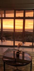 a table with flowers on top of a room with a sunset at Beachfront 3-bedroom with Robben Island views in Cape Town