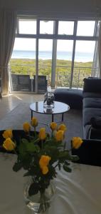 a living room with yellow roses in a vase on a table at Beachfront 3-bedroom with Robben Island views in Cape Town