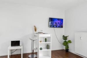uma sala de estar com um armário branco e uma televisão na parede em Entspanntes Wohnen in Düren em Düren - Eifel