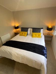 um quarto com uma grande cama branca com almofadas amarelas em Number 57 Brynteg em Caernarfon