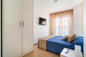a bedroom with a bed with blue sheets and a tv at Apartamentos Delamar in Carboneras