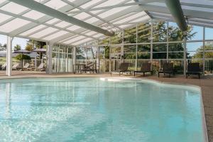 a swimming pool with a white pergola at VVF Pointe Bretagne, Argol in Argol