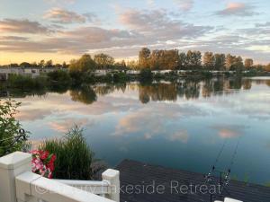 uma vista para um lago com uma vara de pesca na água em Lakeside Retreat With Hot Tub & Fishing Peg at Tattershall Lakes Country Park em Tattershall