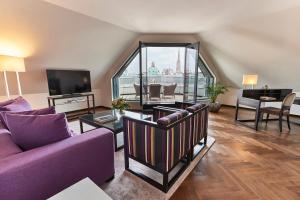 a living room with purple furniture and a large window at Steigenberger Hotel Herrenhof in Vienna