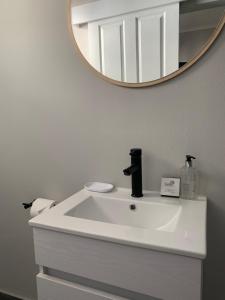 lavabo con espejo redondo encima en Luxury Suites on Santorini en East London
