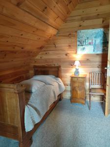 a bedroom with a bed in a log cabin at Chambre d'hôtes - Le jardin des Patissons in La Foret Du Parc