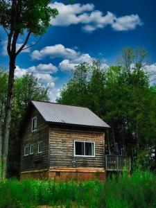 an old wooden house in the middle of a field at Juniper Cabin- Waterfront retreat on Mosque Lake in Ompah