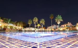 a large pool of water with palm trees at night at Apartamentos Honorio - Pool and Garden in Vilamoura