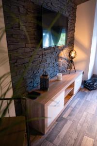 a living room with a tv on a brick wall at Ô Cocoon de Mya in Gedinne