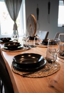 een houten tafel met borden en wijnglazen erop bij Ô Cocoon de Mya in Gedinne