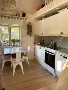 a kitchen with white cabinets and a table and chairs at Charmigt hus på Vindö in Stockholm