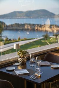 a table with wine glasses and a view of the ocean at Hotel Cala Moresca in Bacoli