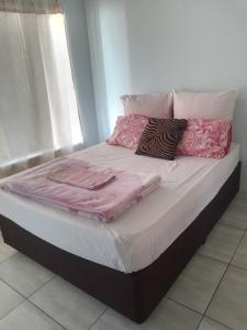 a bed with pink blankets and pillows on it at Cossy Possy Guest House in Johannesburg