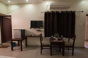a room with a table and chairs and a television at Arunik Inn in Puducherry