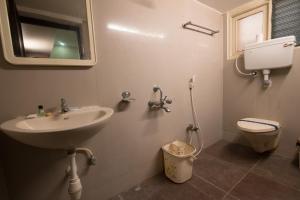 a bathroom with a sink and a toilet and a mirror at Arunik Inn in Puducherry