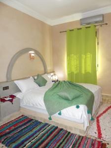 een slaapkamer met een groot bed en een groen gordijn bij Dar Diafa Chez Anaam in Er Rachidia