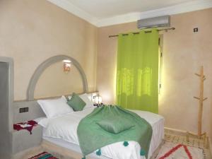 een slaapkamer met een bed met een groen gordijn bij Dar Diafa Chez Anaam in Er Rachidia