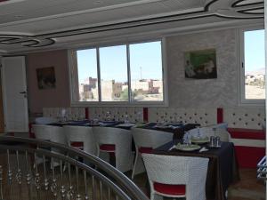 a dining room with tables and chairs and windows at Dar Diafa Chez Anaam in Er Rachidia