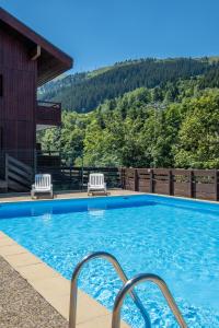a swimming pool with two chairs and a house at Résidence Pierre & Vacances Le Peillon in Méribel +42 photos