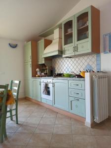 uma cozinha com armários verdes e um fogão forno superior em sa janna em Orosei