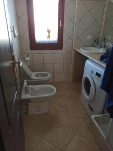 een badkamer met een wastafel, een toilet en een raam bij sa janna in Orosei