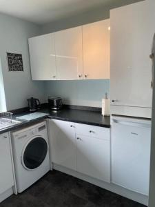 a kitchen with white cabinets and a washing machine at Seaview Apartment with parking in Exmouth