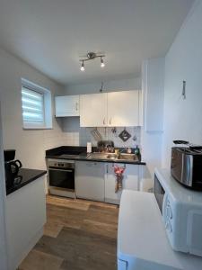 uma cozinha com armários brancos e um forno com placa de fogão em La Colonne em Obernai