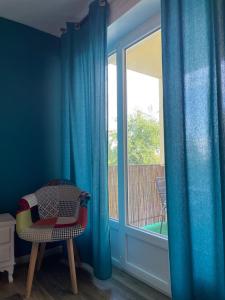 um quarto azul com uma cadeira e uma janela em La Colonne em Obernai