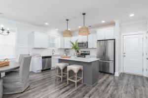 a kitchen with white cabinets and a kitchen island with bar stools at LUXURY BEACH HOUSE W/ BACKYARD OASIS. HEATED POOL. in Hilton Head Island