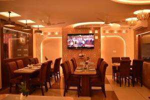 a restaurant with tables and chairs and a tv on the wall at HOTEL KAILASH in Deoria