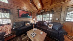 una sala de estar con muebles de cuero en una cabaña de madera en Snoozers Hollow cabin, en Sevierville