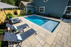 un patio trasero con piscina, sillas y una casa en LUXURY BEACH HOUSE W/ BACKYARD OASIS. HEATED POOL., en Hilton Head Island