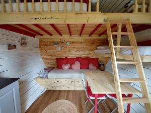L'authentique Tonneau à Cidre d'Emma في Litteau: سرير بطابقين في غرفة خشبية مع سلم