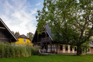 une maison jaune et noire avec un arbre dans l'établissement Ferienwohnung Rehblick Spreewaldferien-Burg, à Burg